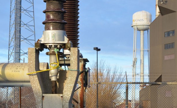 close up of part of electrical station equipment, with water tower in the background with word Ponds written on it