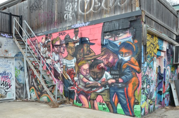 metal stairs in front of a large mural by elicser elliott of a policeman controlling a crowd