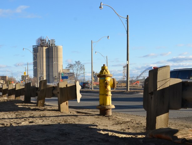 yellow fire hydrant in front, guard rails along the side of Lakeshore Blvd, with Lafarge silos in the background