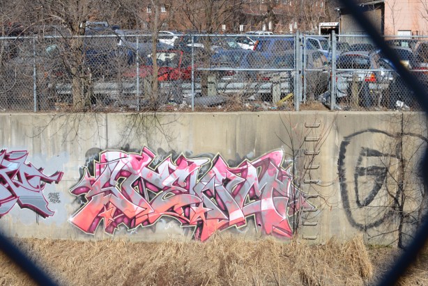 pink and white text graffiti on a canal wall 