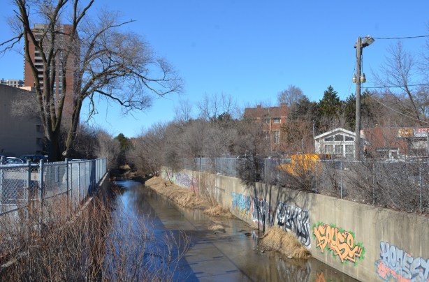 waterway with concrete sides, graffiti on the walls, some water, 
