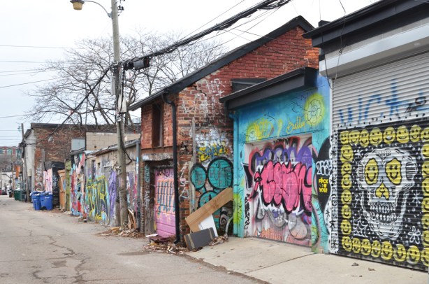 garages in a lane with graffiti and street art on them 