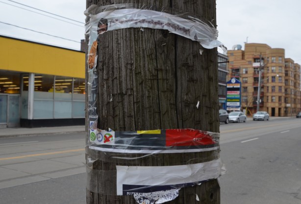 a poster on a wood utility pole has been torn but the four edges remain