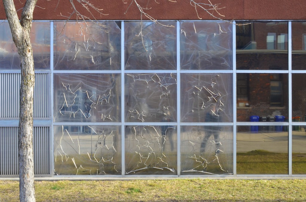 exterior view of a window that had clear plastic on it.  plastic is ripping and peeling