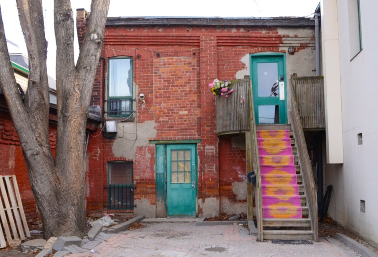 a bright pink and orange carpet on the stairs leading to the second storey behind an old brick building in Liberty Village