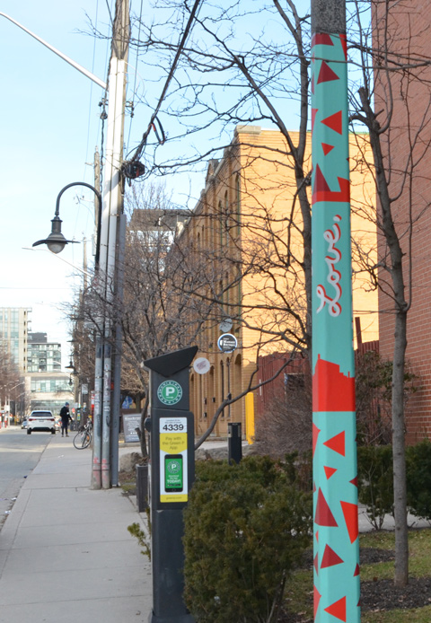 street in Liberty Village, one utility pole is painted in turquoise with red triangles and the word Love written in cursive