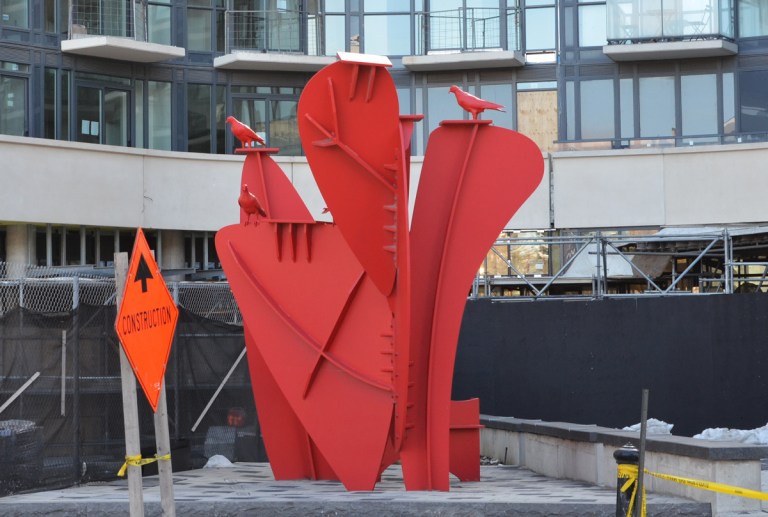 Red metal sculpture in front of a new condo development in Liberty Village, with red metal pigeons on top of the shapes