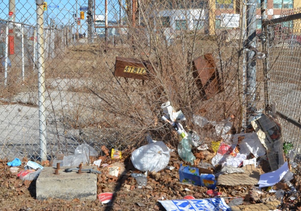 chainlink fence with rusty mailboxes, a lot of garbage has blown up against the fence 