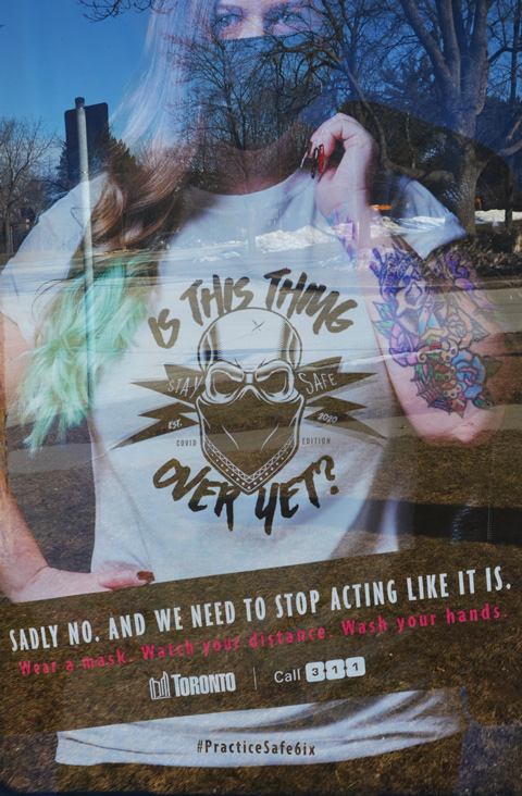 poster in a bus shelter, Covid-19, how it isn't over yet, practice safe six 