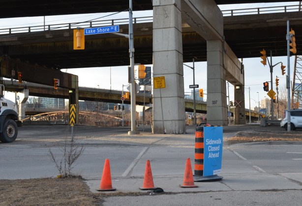 at the intersection of Don Roadway and Lakeshore Blvd, traffic cones and a blue sign that says sidewalk closed ahead 