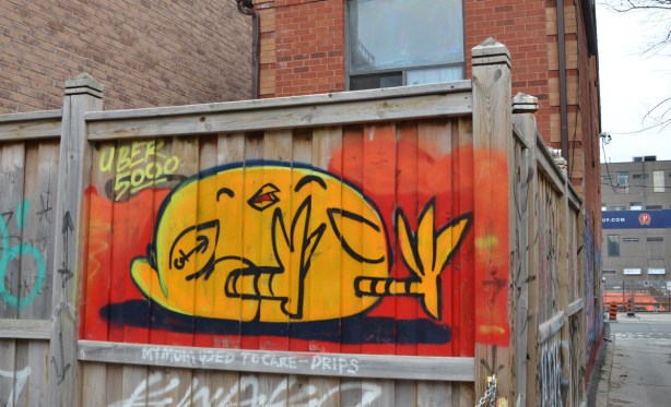 uber 5000 yellow birdie mural, lying on a black surface, feet in air, red background