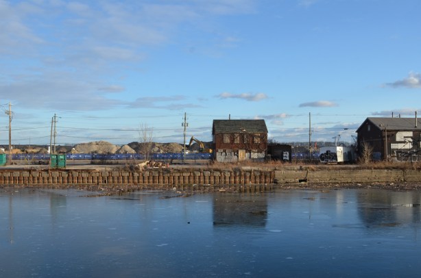 lone building onthe other side of the water, surrounded by construction at ground level.  boarded up, two storey building