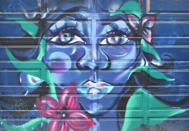 mural on a garage door, womans face in blue and purple