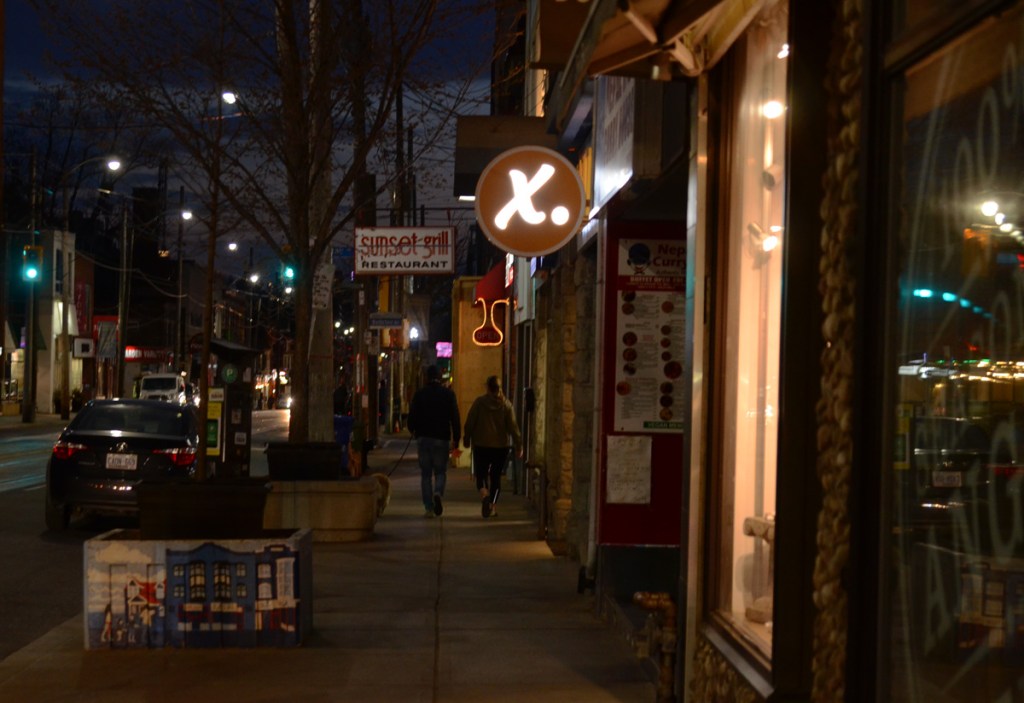 a couple walk down the sidewalk, late evening as it gets dark