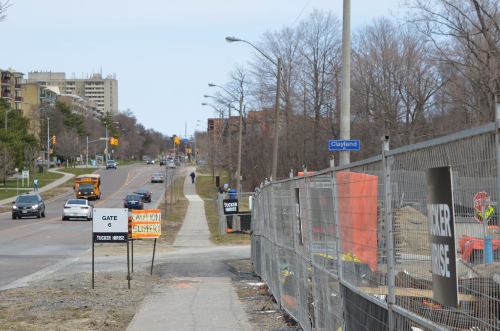 Looking east along York Mills Road, just east of the Don Valley Parkway, some condo construction on the right, traffic, school bus, low rise apartments on the left