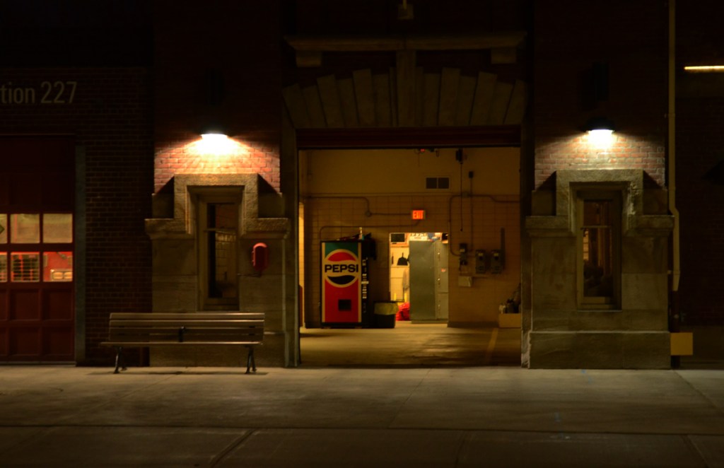 night, exterior of firehall 227, open door showing interior and pepsi vending machine, bench on sidewalk, 