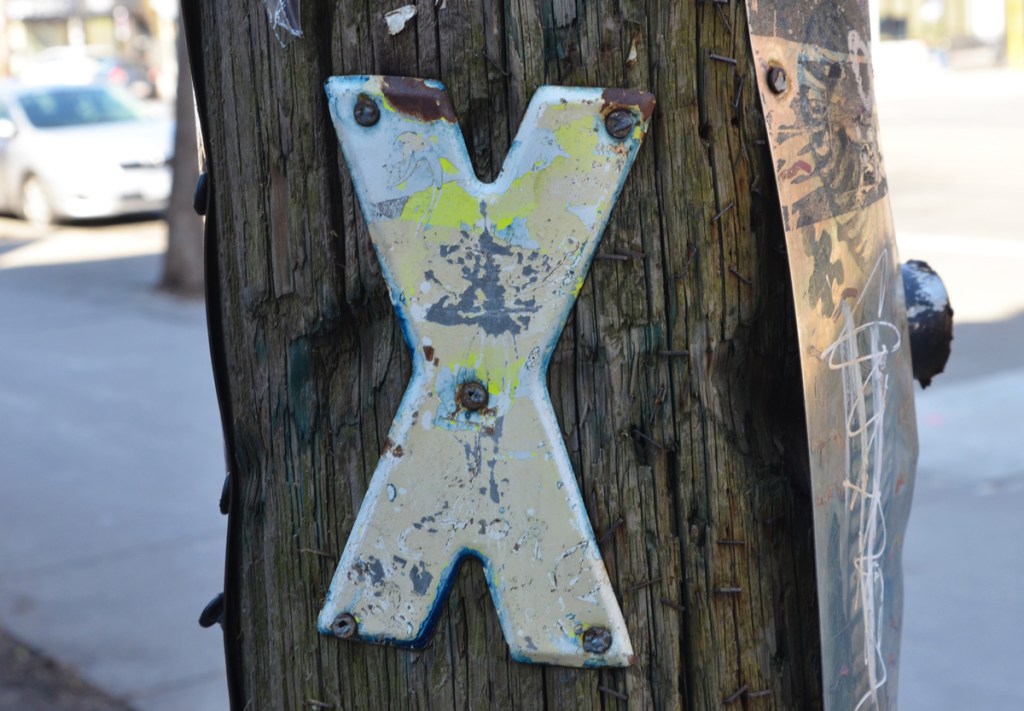 metal in the shape of an X screwed onto a wood utility pole
