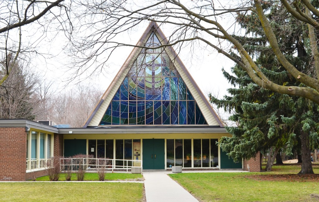 Front view of Our Saviour Church, Anglican, with its A shaped roof line.  Large triangular stained glass window 