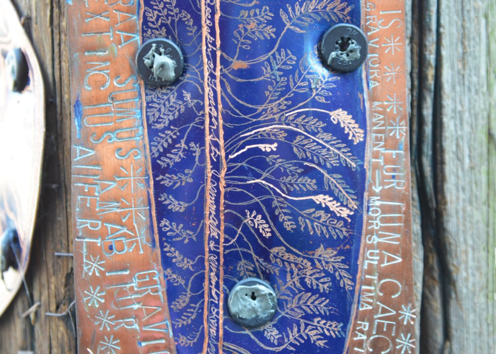 Leaf like designs in an oval shape with Latin words written around the outside 