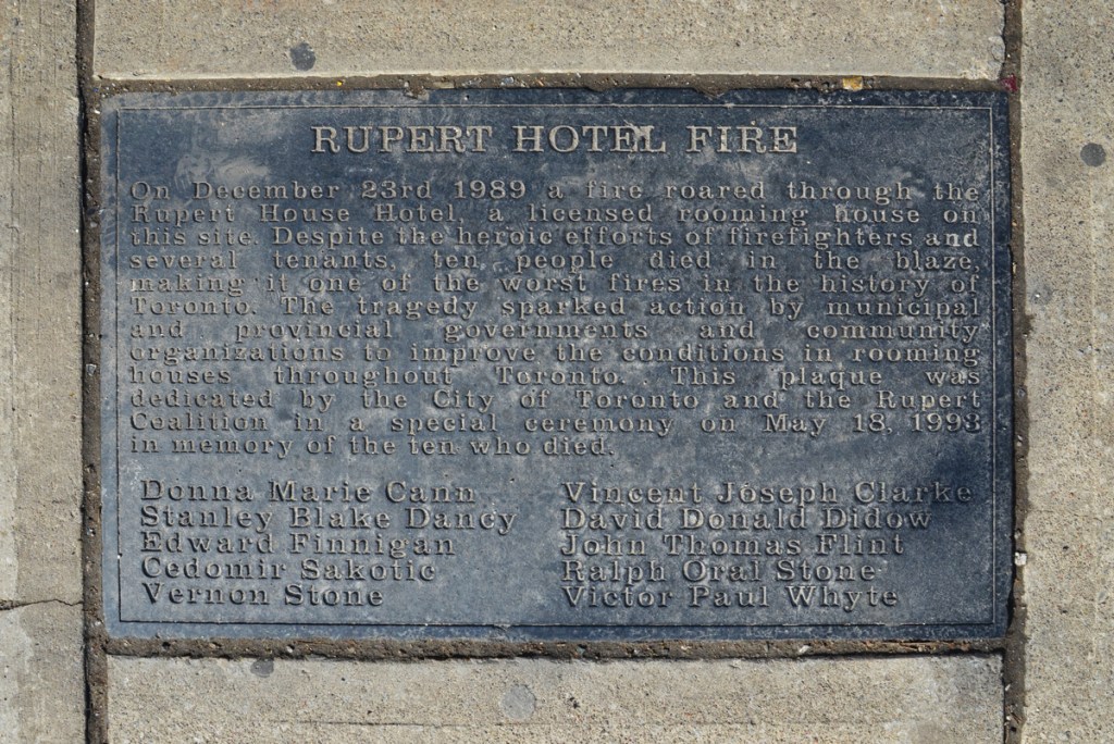 Plaque in the sidewalk describing the Rupert Hotel fire of 1989 when a rooming house burned down, killing 8 people