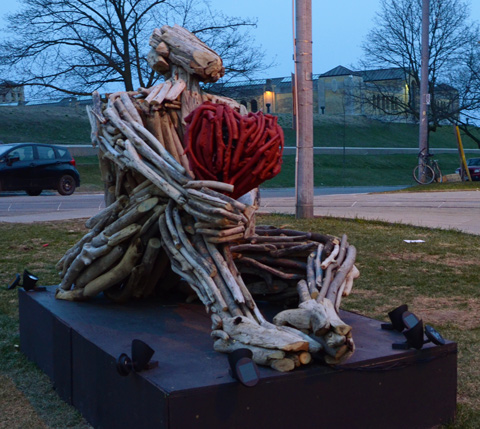 Luminosity installation person holding a large red heart, with R C Harris filtration plant in the background