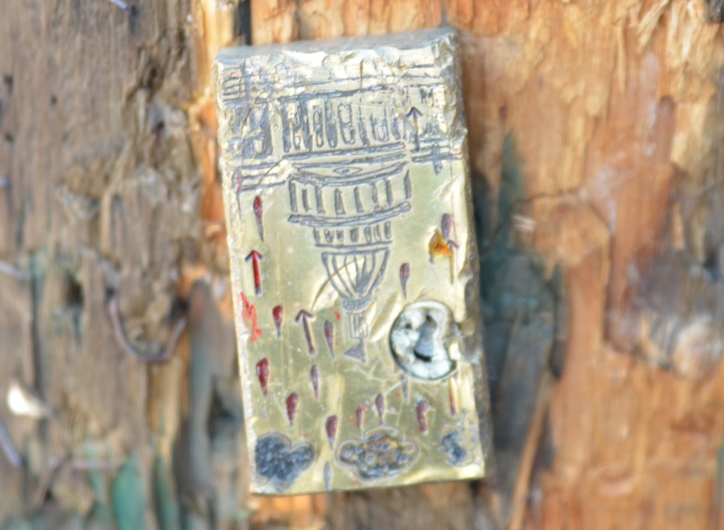 very small engraving of a domed building with clouds and rain drops, graffiti or street art on a pole