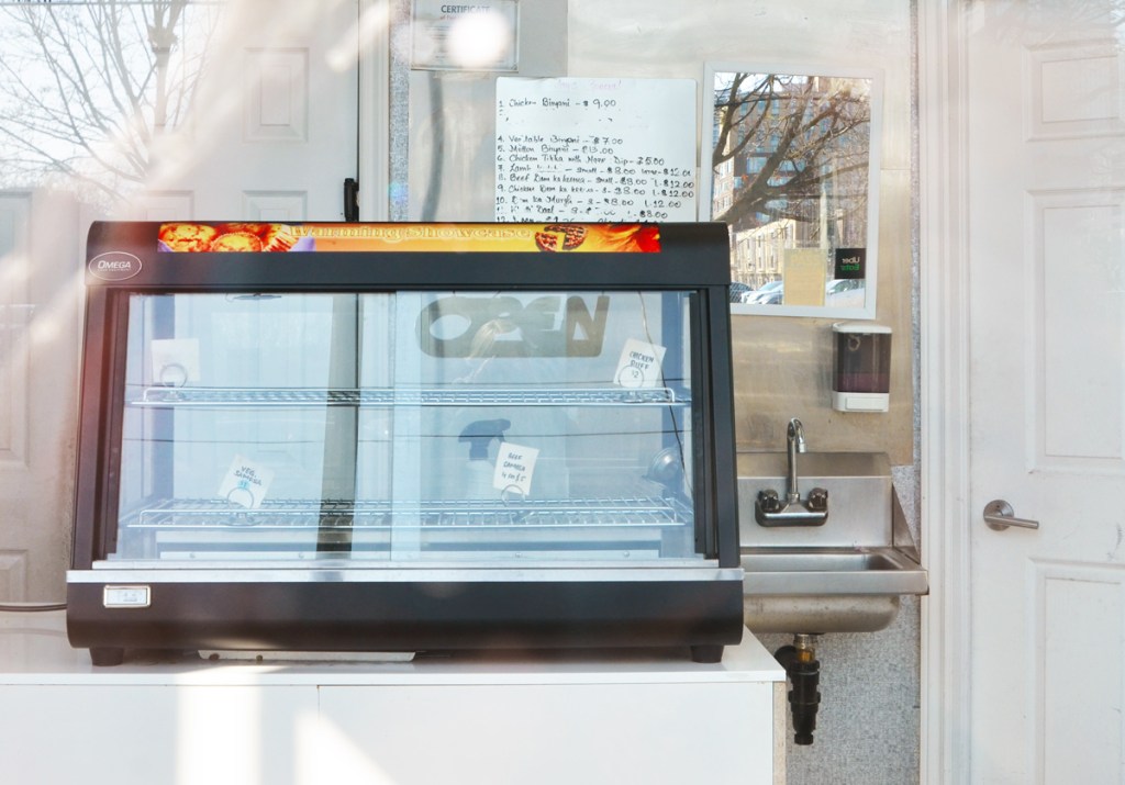 empty kitchen and restaurant, looking through the window into, with reflections of trees and cars in the window too
