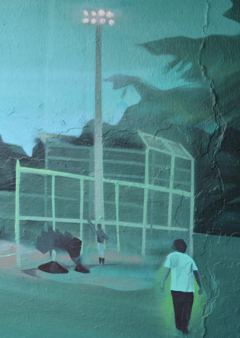 A boy walks towards the back of a baseball diamond with its overhead lights 