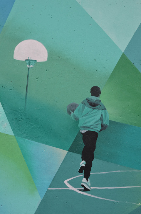 a young boy plays basketball, holding basketball, hoop in background