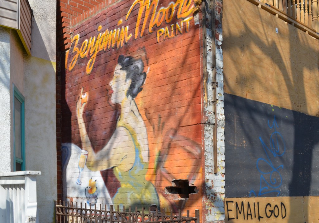 mural of a seated woman on a brick wall, an advert for Benjamin Moore paint 