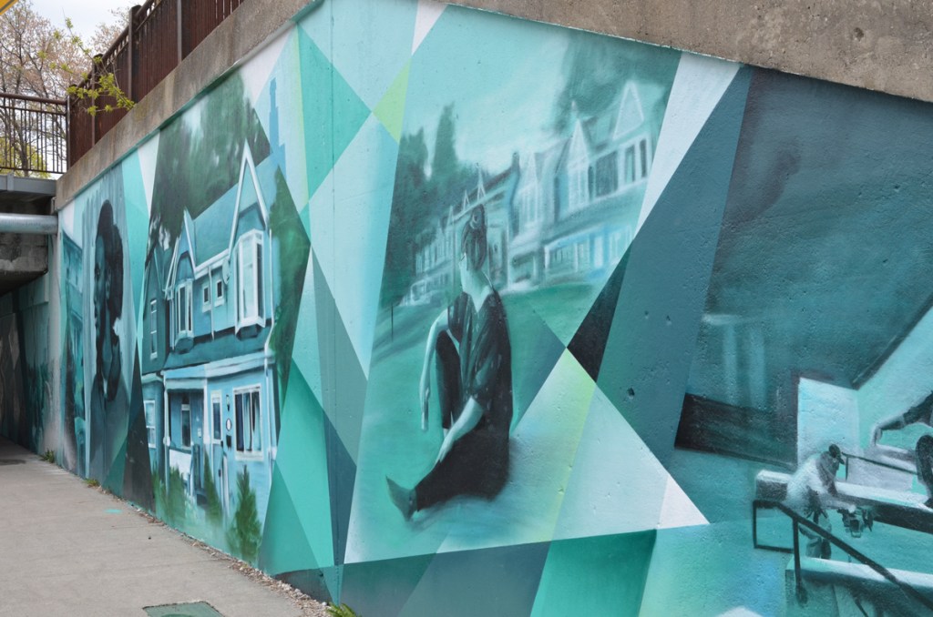 part of mural painted by Jason Pinney onJones Ave, a woman sitting outside, a two storey semi-detached house