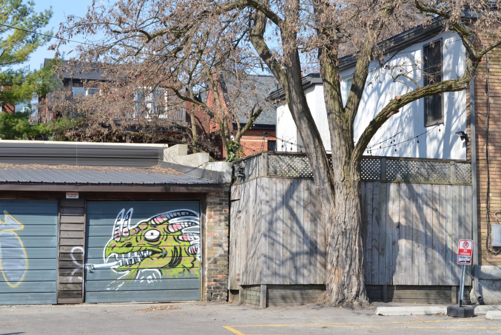 green dragon or monster head on a blue garage door, big white eyes, horns, big mouth with white teeth