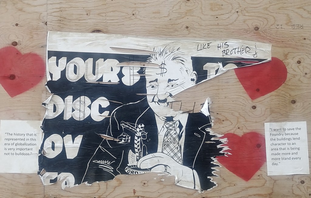 red hearts stenciled on plywood hoardings along with a poster showing parody of Doug Ford with his hands meddling with a model of Toronto City Hall.  Other posters with words describing why saving the old Dominion Wheel Foundry is important 