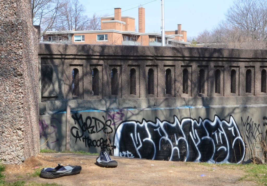 an abandoned pair of shoes on the ground beside concrete railing of bridge over Rosedale Valley Road