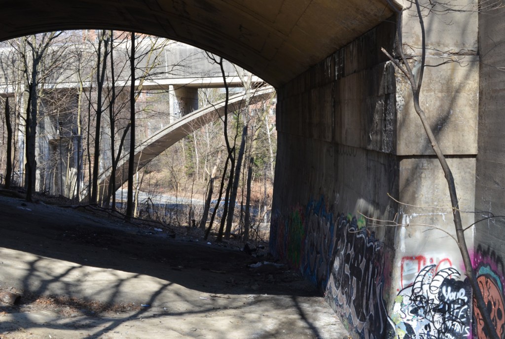 looking through arch in bridge to another bridge. the one in the background is the covered bridge for the TTC subway between Sherbourne and Castle Frank stations