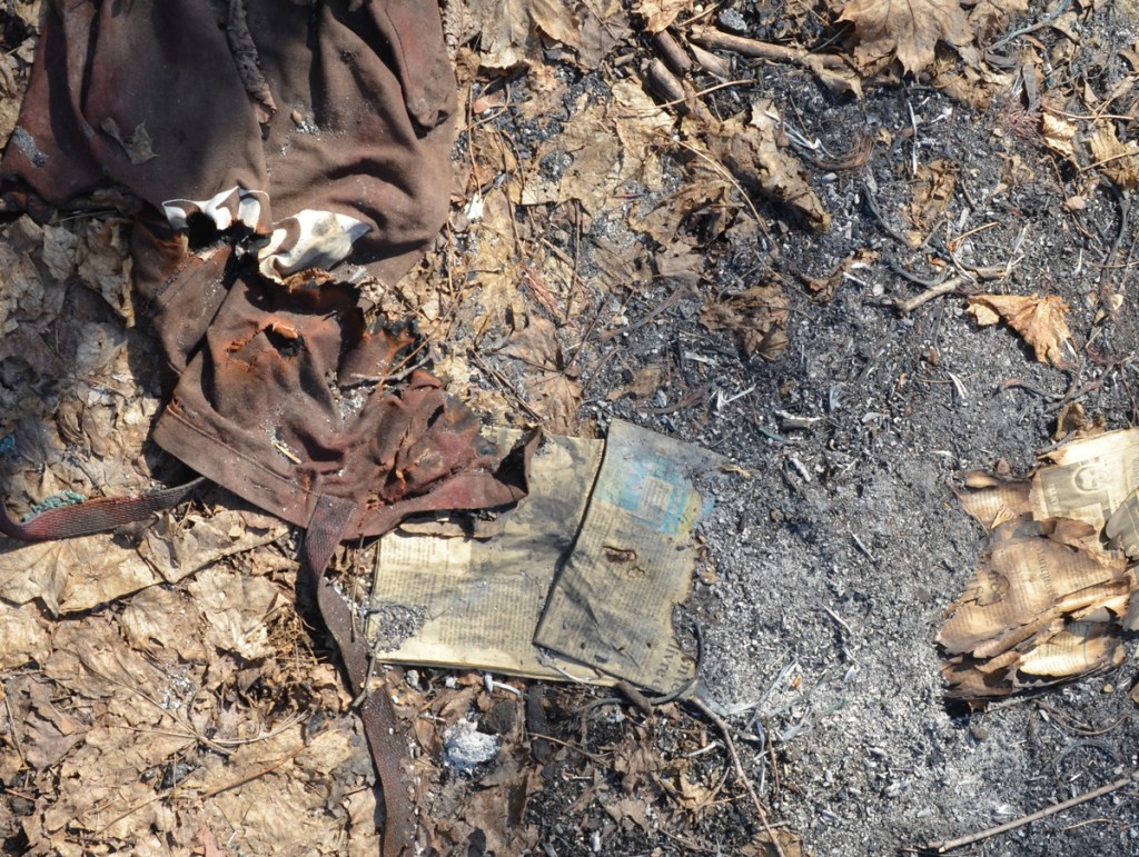 garbage on the ground, an old piece of clothing and some paper, looks like has been partially burned