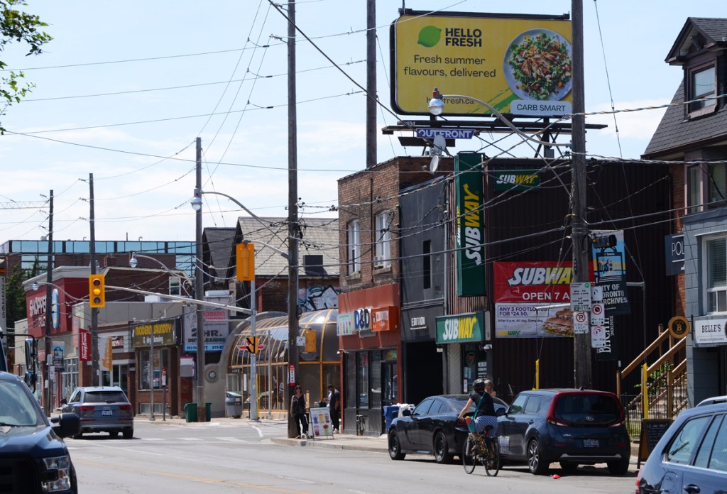 north side of Dupont, Spadina through the middle of the picture, round structure of Dupont subway station, billboard over the building on the northeast corner