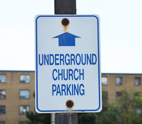 sign with an arrow pointing straight ahead and words that say underground church parking