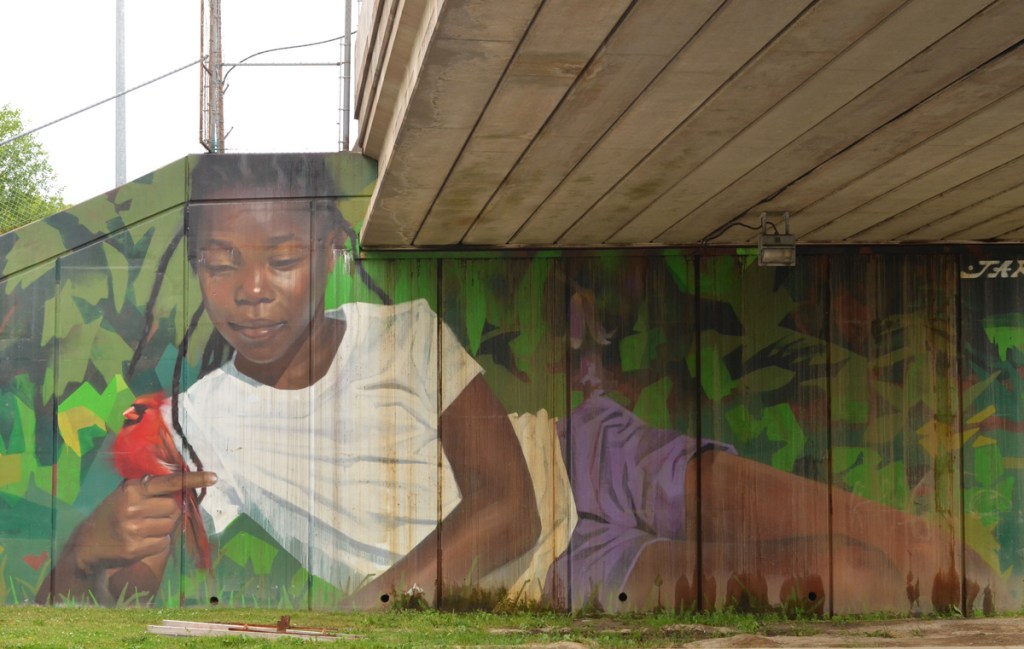 mural by Jarus of a young girl holding a cardinal bird, beside sidewalk on TTC subway underpass Pharmacy Ave in Scarborough