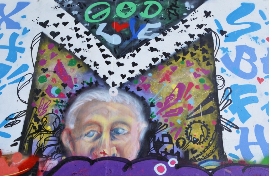 close up of old woman in mural, words god and love are written above her, some symbols beside her, lots of little hearts 