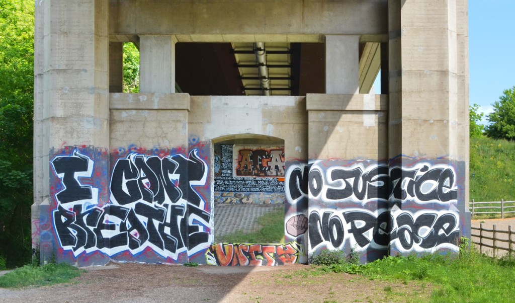 BLM mural on bridge supports, I can't breath, no justice, no peace are words painted on it, also a wall full of names of those who have died  