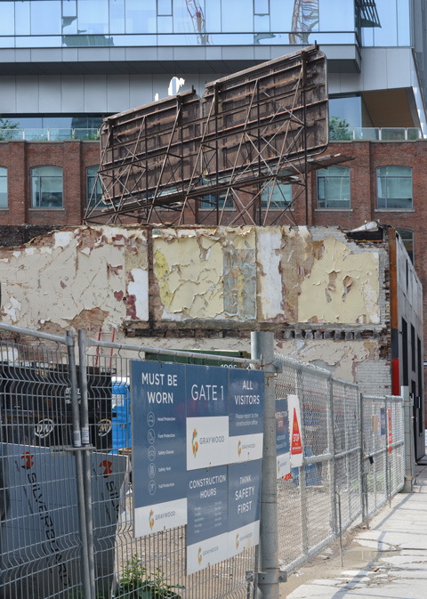 chainlink fence and gate at construction site, remnants of interior wall still show old walls that were once pale yellow