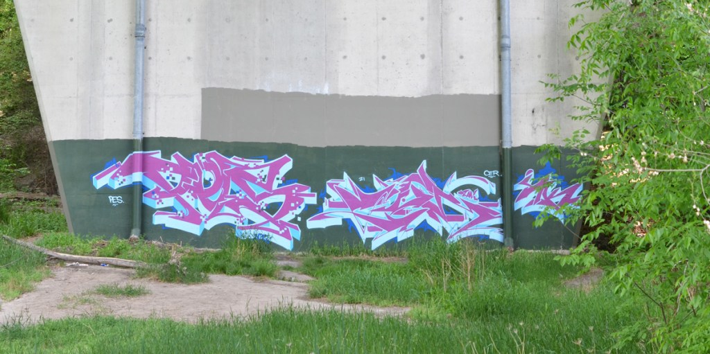 pink and white tag graffiti, text, calligraphy, on dark green background on lower part of concrete bridge support