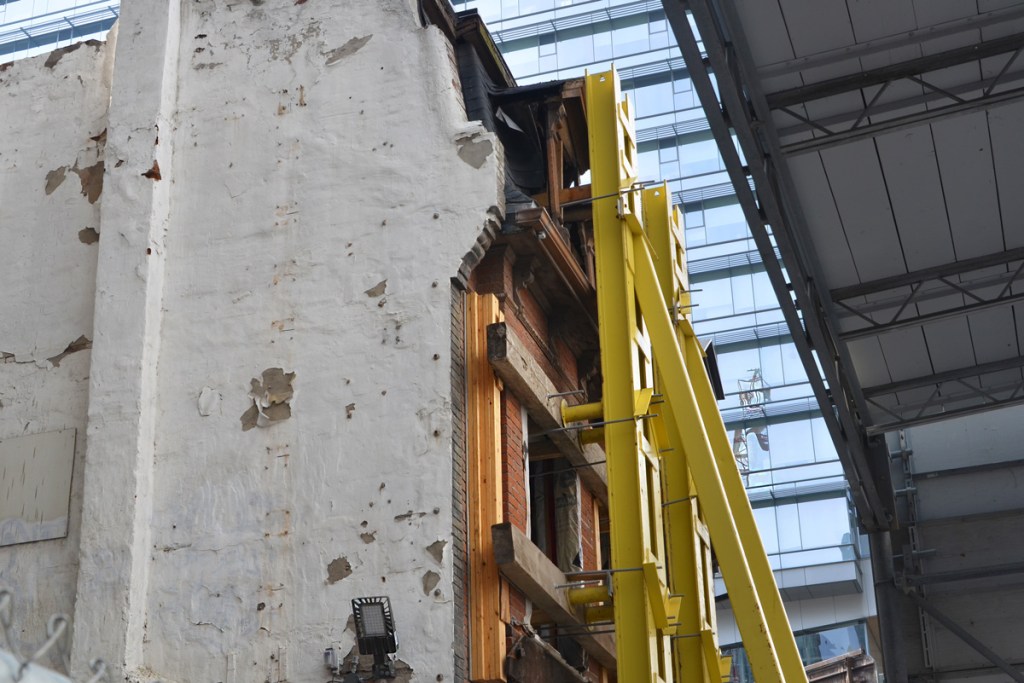 yellow metal scaffolding to keep up the brick facade of an old building while the rest of it is demolished. 