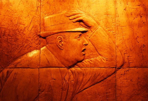 part of relief sculpture at Dundas subway station, a man holds on to his hat as he hurries along
