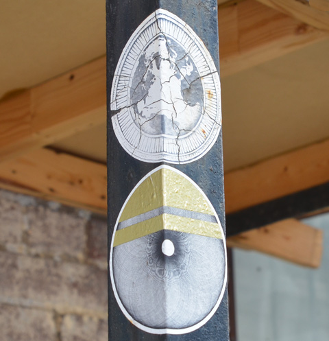 2 round paper paste up slaps on a pole.  The upper one shows a map of the world with the Atlantic Ocean in the center, the lower one is the round part of an eye