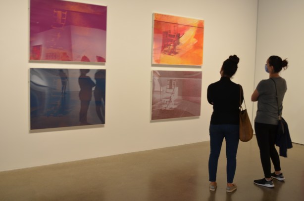 two women look at prints of electric chair in 4 different colour tones