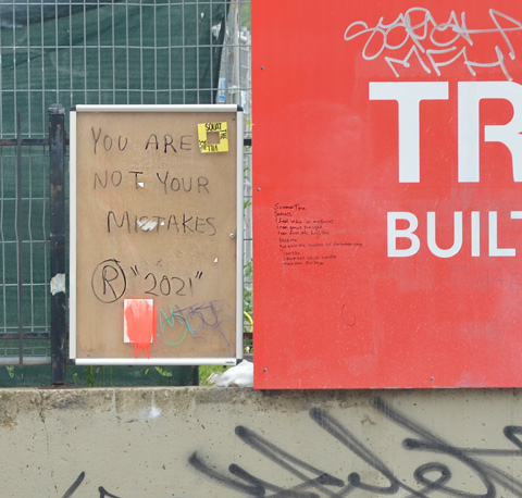 on brown paper, a message that says You are not your mistakes, beside a red Tridel sign. on the latter, someone has written a poem in sharpie