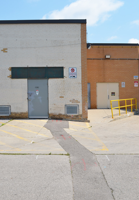 doors, back entrances to stores in mall, with crooked yellow railing and crooked patch in pavement