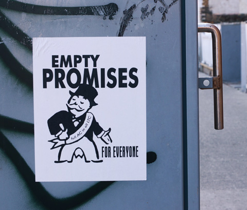 a poster on the side of a grey metal box on sidewalk, man from monopoly and words that say empty promises for everyone, 